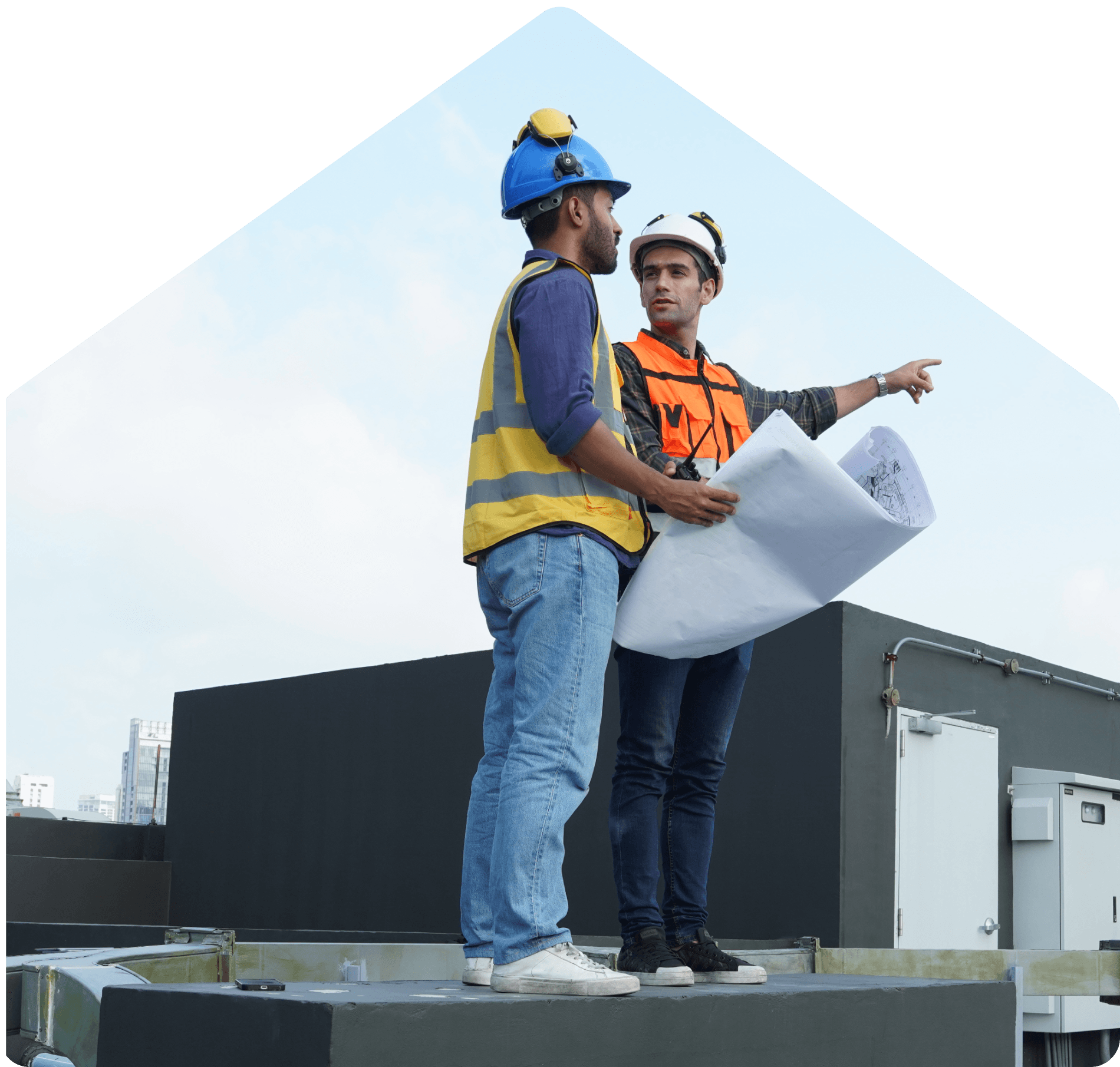 Two engineers inspecting blueprints atop a commercial rooftop